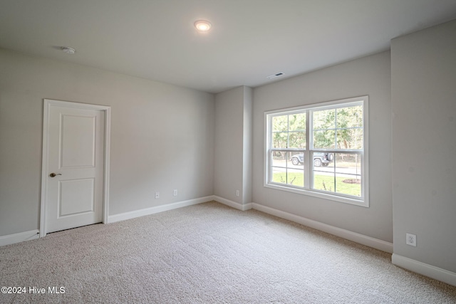 unfurnished room featuring carpet, visible vents, and baseboards