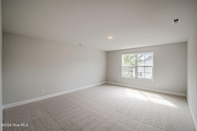 unfurnished room with visible vents, baseboards, and light colored carpet