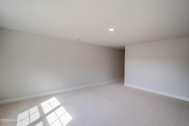 spare room with recessed lighting, light colored carpet, and baseboards