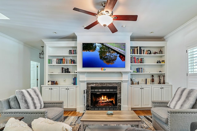 living room featuring crown molding, a high end fireplace, light hardwood / wood-style floors, and ceiling fan