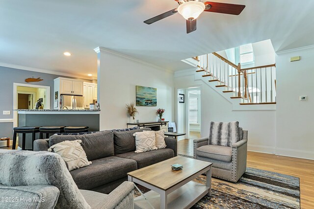 living room with ornamental molding, ceiling fan, and light hardwood / wood-style flooring