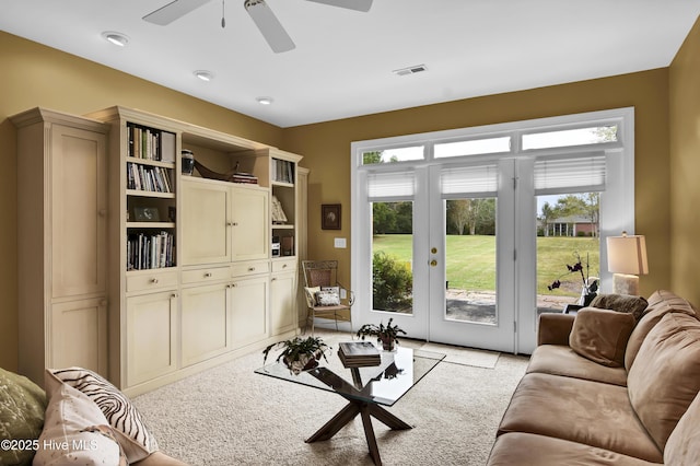 living room with visible vents, light colored carpet, and a ceiling fan