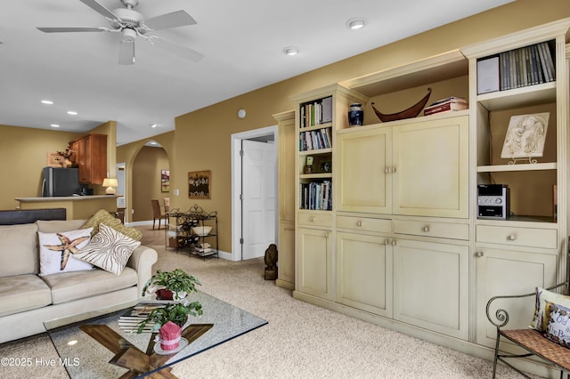 living room featuring a ceiling fan, baseboards, recessed lighting, arched walkways, and light carpet