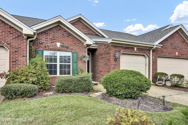 ranch-style home with brick siding, a garage, and roof with shingles