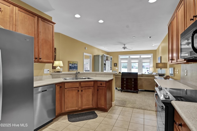 kitchen with a sink, open floor plan, appliances with stainless steel finishes, a peninsula, and light countertops