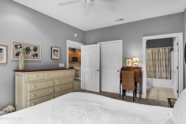 carpeted bedroom with tile patterned floors, visible vents, connected bathroom, and ceiling fan