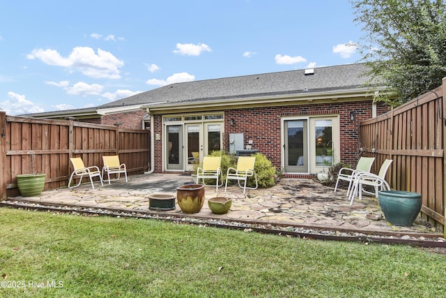 rear view of house with a patio area, brick siding, and a fenced backyard