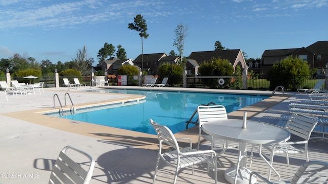 pool with a patio, fence, and a residential view