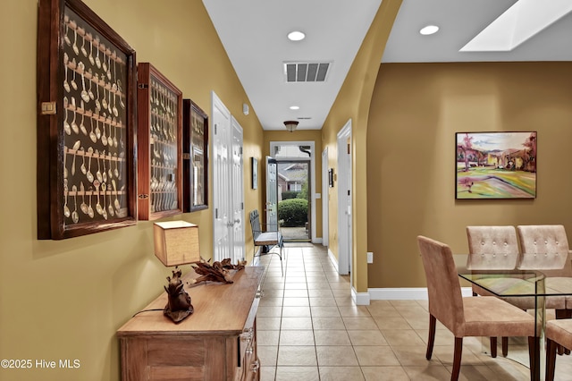 interior space featuring baseboards, visible vents, a skylight, light tile patterned flooring, and recessed lighting