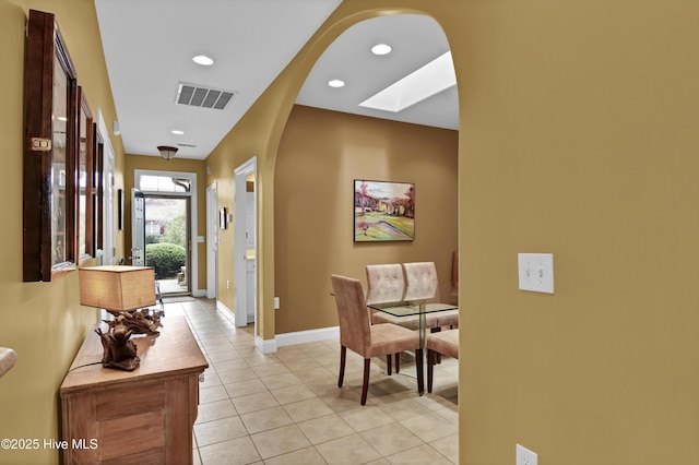 hallway with light tile patterned floors, visible vents, baseboards, recessed lighting, and arched walkways