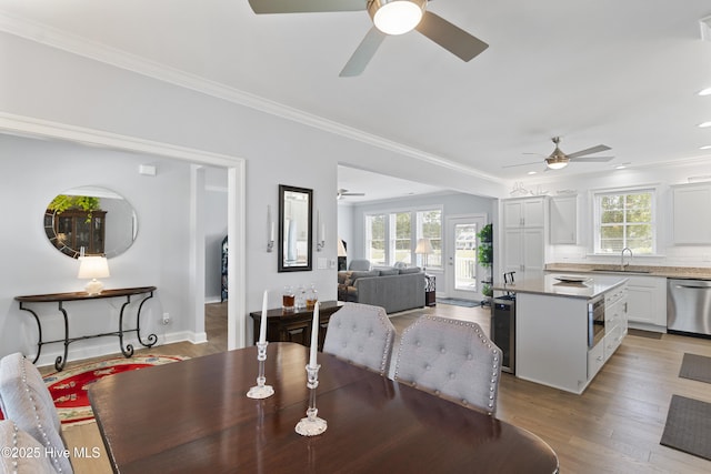 dining area with light wood-type flooring, ornamental molding, and sink