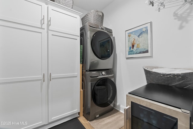 clothes washing area with wine cooler, stacked washer and dryer, and cabinets