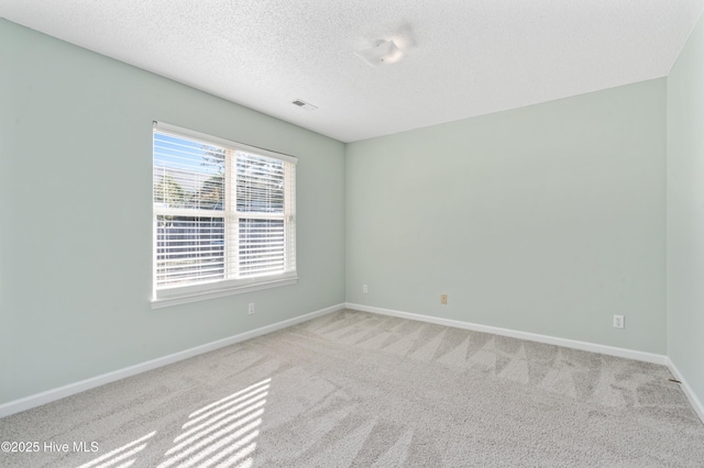 spare room with a textured ceiling and light colored carpet