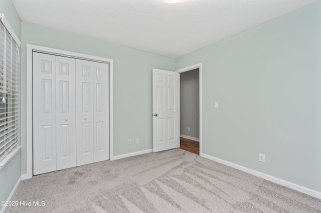 unfurnished bedroom featuring light carpet, a closet, and a textured ceiling