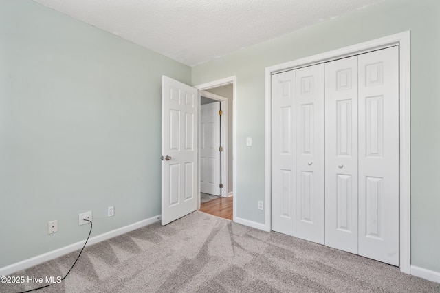 unfurnished bedroom featuring a closet, light colored carpet, and a textured ceiling