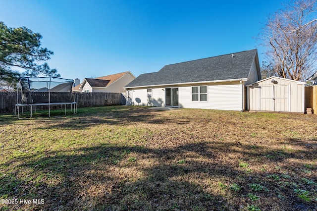 back of property featuring a storage unit, a trampoline, and a yard