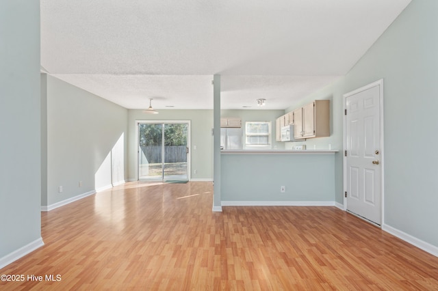 unfurnished living room featuring a textured ceiling and light hardwood / wood-style floors