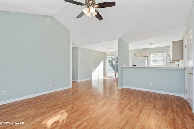 unfurnished living room featuring a textured ceiling, ceiling fan, light hardwood / wood-style flooring, and vaulted ceiling