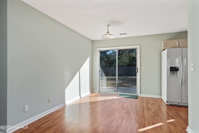 unfurnished dining area featuring a textured ceiling and light hardwood / wood-style floors