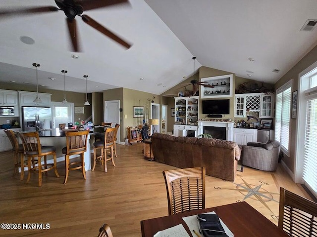 dining space with vaulted ceiling, ceiling fan, and light hardwood / wood-style floors