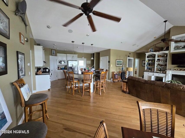 dining area featuring ceiling fan, lofted ceiling, and light hardwood / wood-style floors