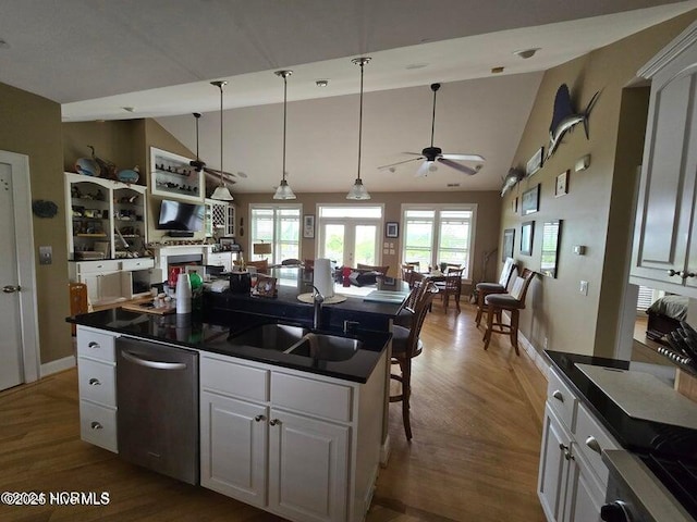 kitchen featuring sink, a breakfast bar area, vaulted ceiling, stainless steel dishwasher, and white cabinets