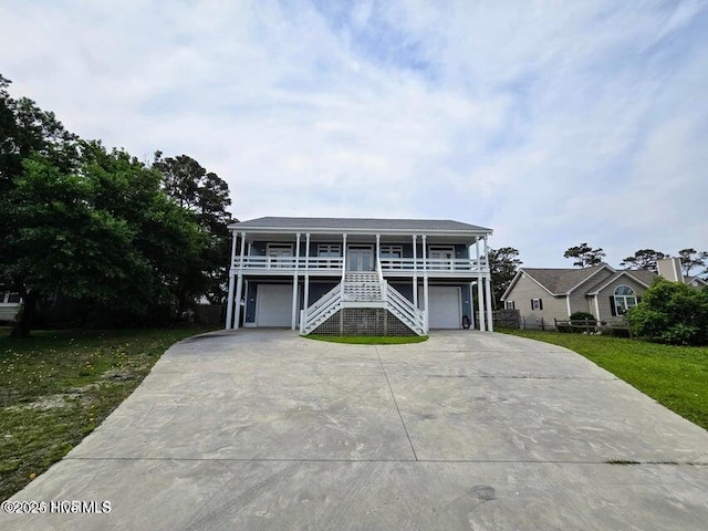 coastal home with a porch, a garage, and a front yard