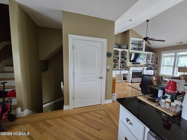 kitchen featuring white cabinetry, light hardwood / wood-style flooring, ceiling fan, and vaulted ceiling