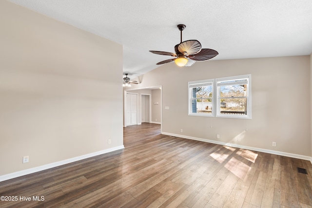 spare room featuring vaulted ceiling, a textured ceiling, and hardwood / wood-style flooring