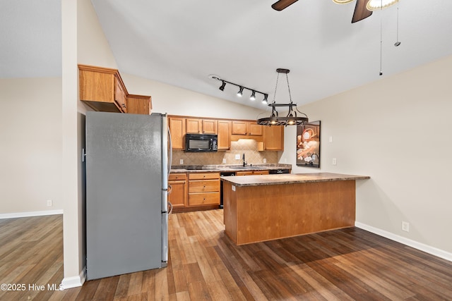 kitchen featuring tasteful backsplash, vaulted ceiling, black appliances, kitchen peninsula, and sink