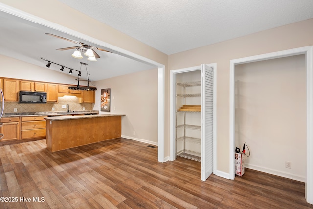 kitchen featuring a textured ceiling, decorative backsplash, hanging light fixtures, dark hardwood / wood-style floors, and kitchen peninsula