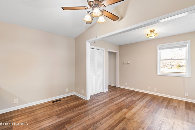 unfurnished bedroom featuring ceiling fan, a closet, vaulted ceiling, and hardwood / wood-style flooring