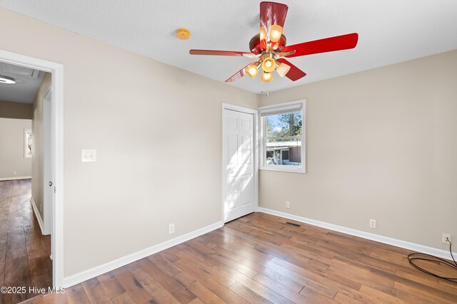 empty room with ceiling fan and dark hardwood / wood-style floors