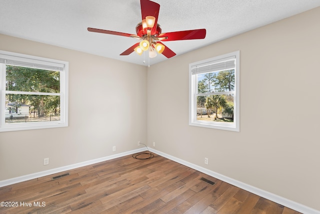 empty room featuring ceiling fan, plenty of natural light, and hardwood / wood-style floors