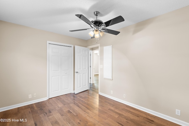 unfurnished bedroom with ceiling fan, dark hardwood / wood-style floors, and a closet