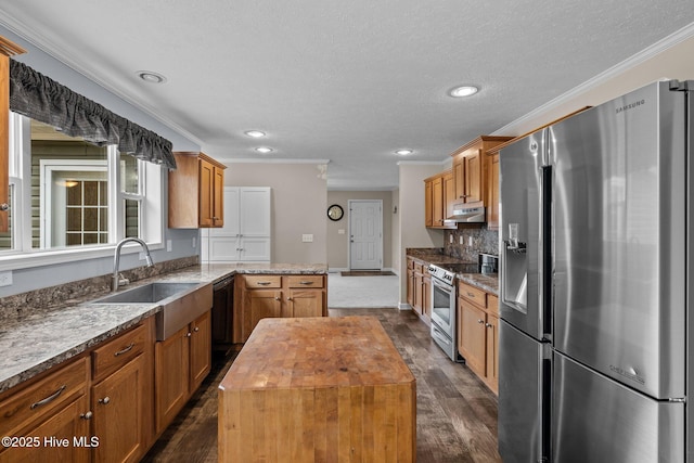 kitchen featuring a center island, crown molding, sink, butcher block countertops, and stainless steel appliances