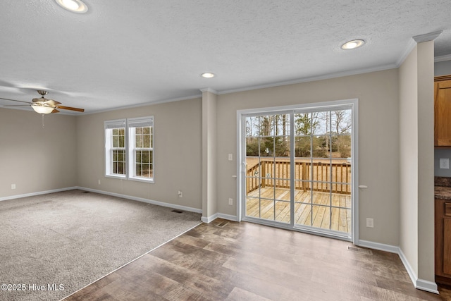 empty room with carpet flooring, a textured ceiling, ceiling fan, and ornamental molding