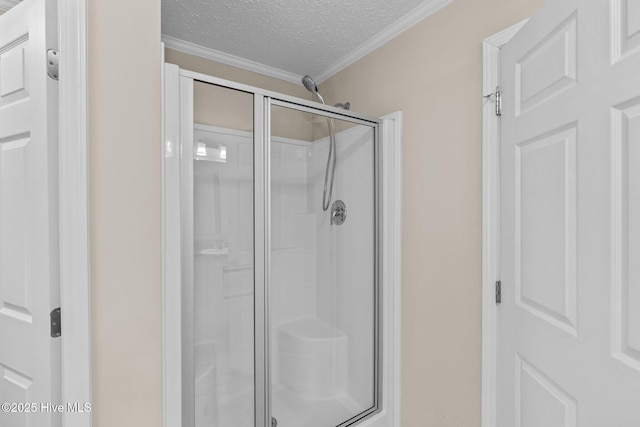 bathroom featuring a textured ceiling, walk in shower, and ornamental molding