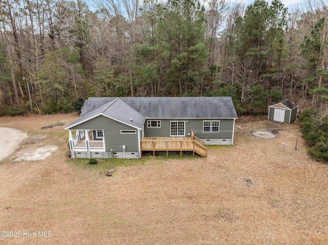 rear view of property featuring a wooden deck and a storage unit