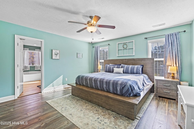 bedroom featuring ensuite bath, ceiling fan, dark wood-type flooring, and a textured ceiling