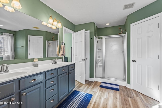 bathroom featuring wood-type flooring, vanity, a textured ceiling, and a shower with door