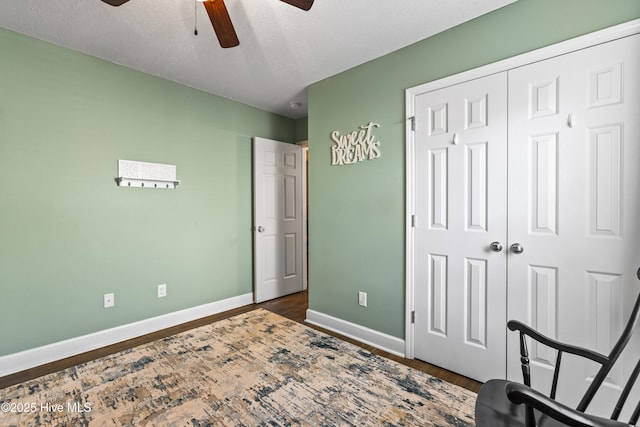 bedroom with ceiling fan, dark hardwood / wood-style flooring, a textured ceiling, and a closet