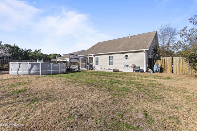 rear view of property featuring a fenced in pool and a yard