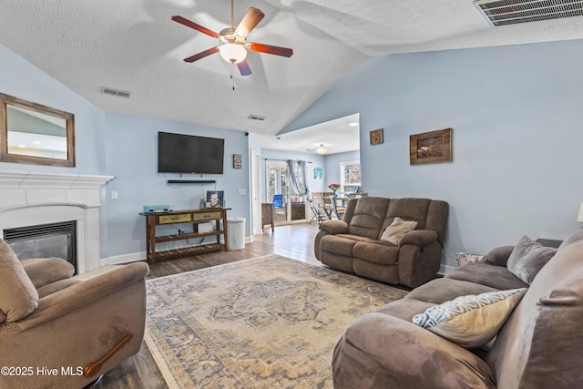 living room with ceiling fan, wood-type flooring, lofted ceiling, and a textured ceiling