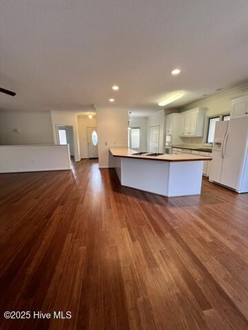 kitchen featuring white cabinetry, white fridge with ice dispenser, hardwood / wood-style floors, and a kitchen island