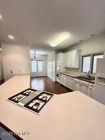 kitchen with sink, crown molding, white appliances, white cabinetry, and dark wood-type flooring