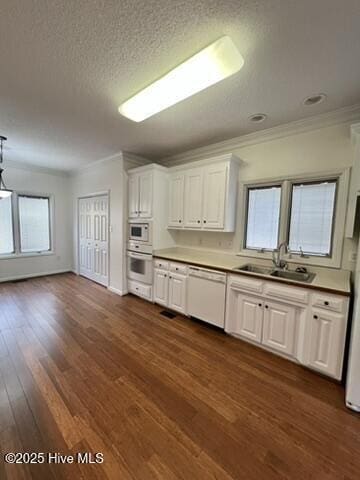 kitchen featuring sink, white appliances, white cabinetry, dark wood-type flooring, and a textured ceiling