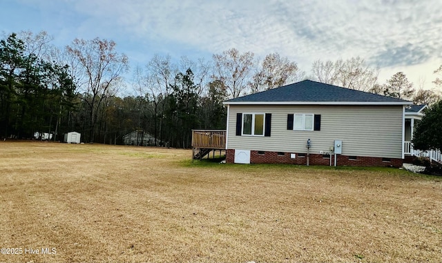 view of side of home featuring a wooden deck, a lawn, and a shed