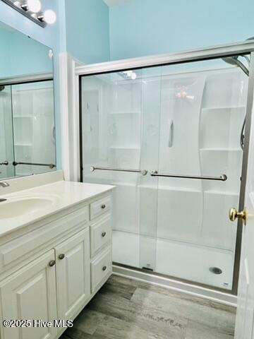 bathroom featuring walk in shower, vanity, and hardwood / wood-style flooring