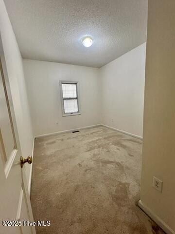 spare room featuring a textured ceiling and carpet floors